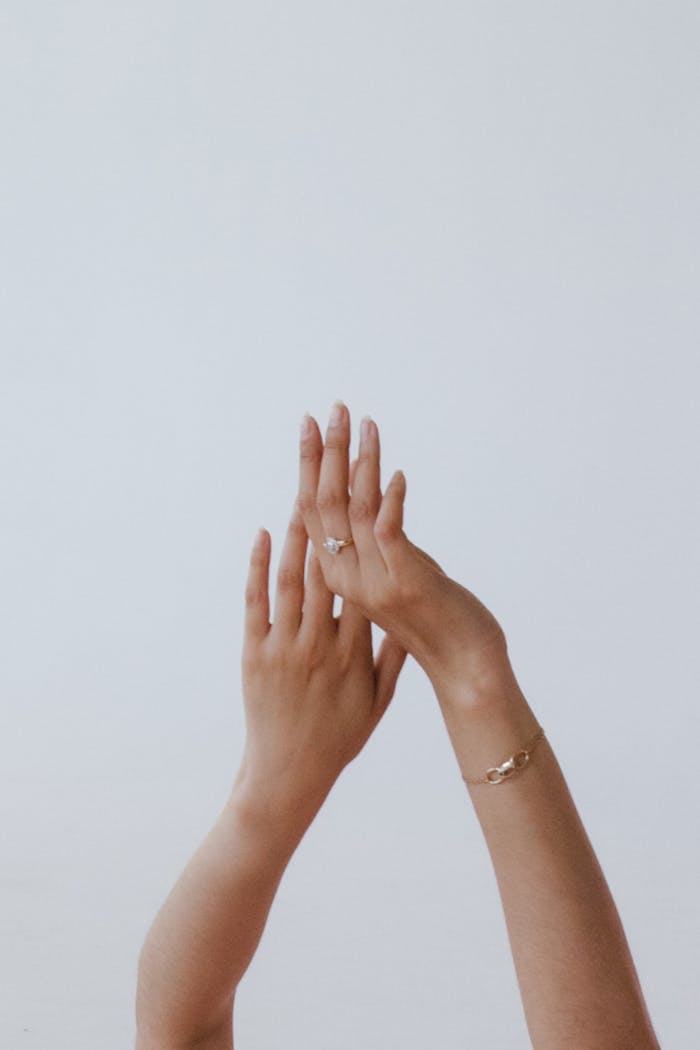 Aesthetic composition of elegant hands adorned with jewelry against a white background, showcasing simplicity and style.